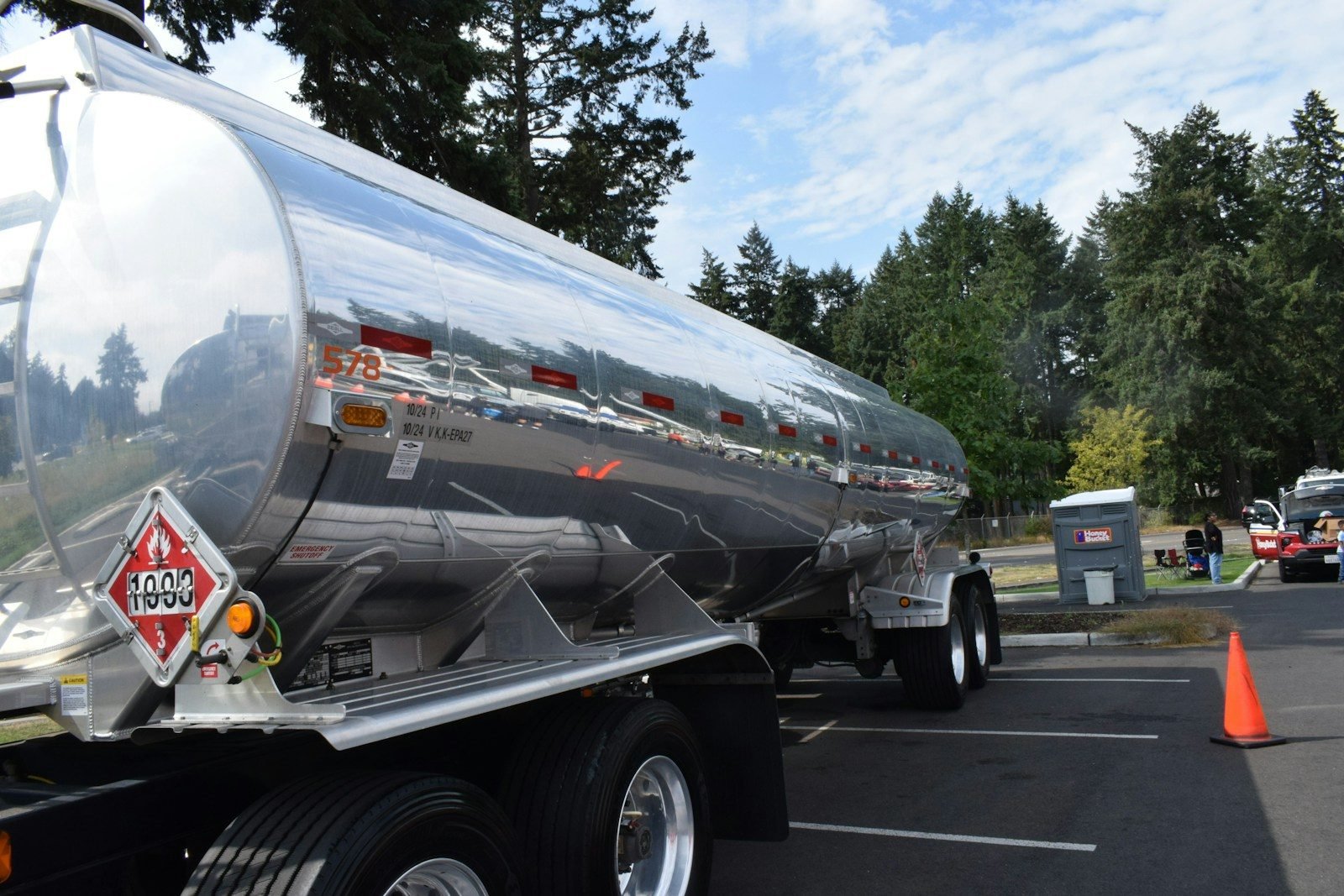 Shiny tanker truck with hazard symbols parked outdoors.